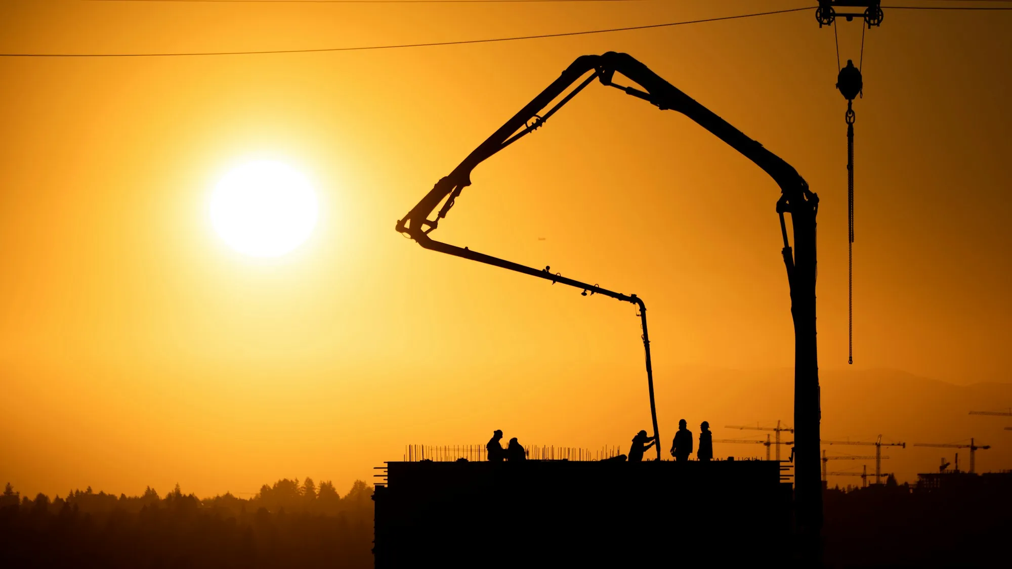 Concrete pump boom silhouetted at sunset