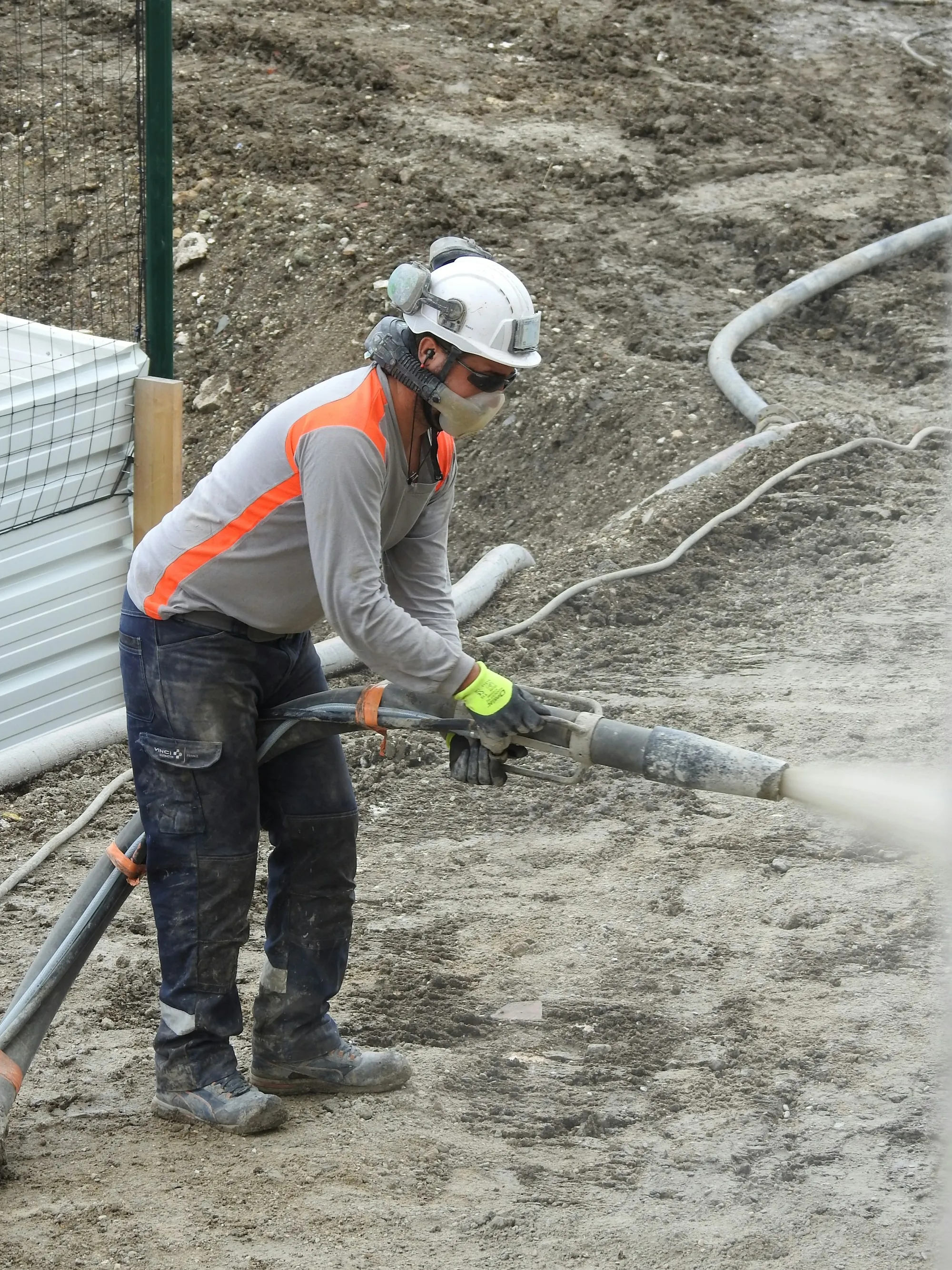 Worker spraying concrete from a hose on a job site